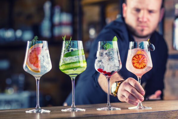 Barman in pub or restaurant  preparing a gin tonic cocktail drinks in wine glasses