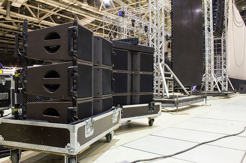 Flight cases with line array speakers. Stage, trusses, led screen and sound speakers background. Installation of professional concert equipment.