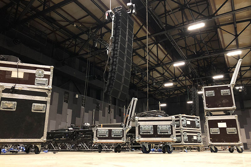 Installation of professional sound speakers, line array, light, video and stage equipment for a concert. Tech zone with flight cases.