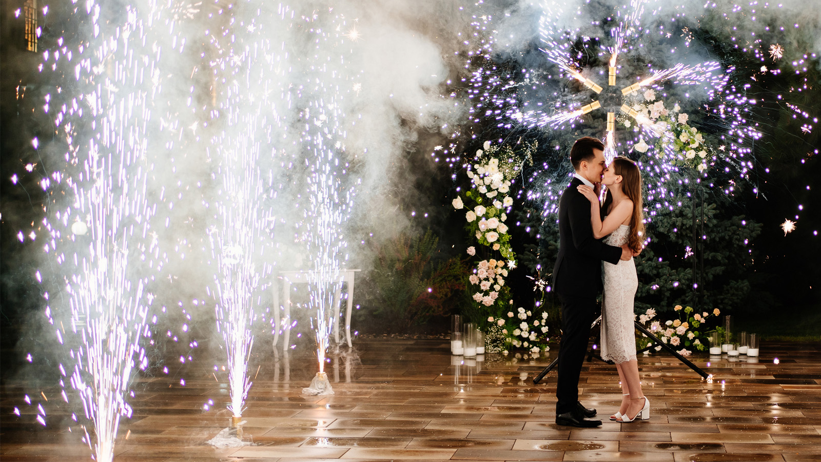 image of a couple at a wedding reception surrounded by flower display and fireworks