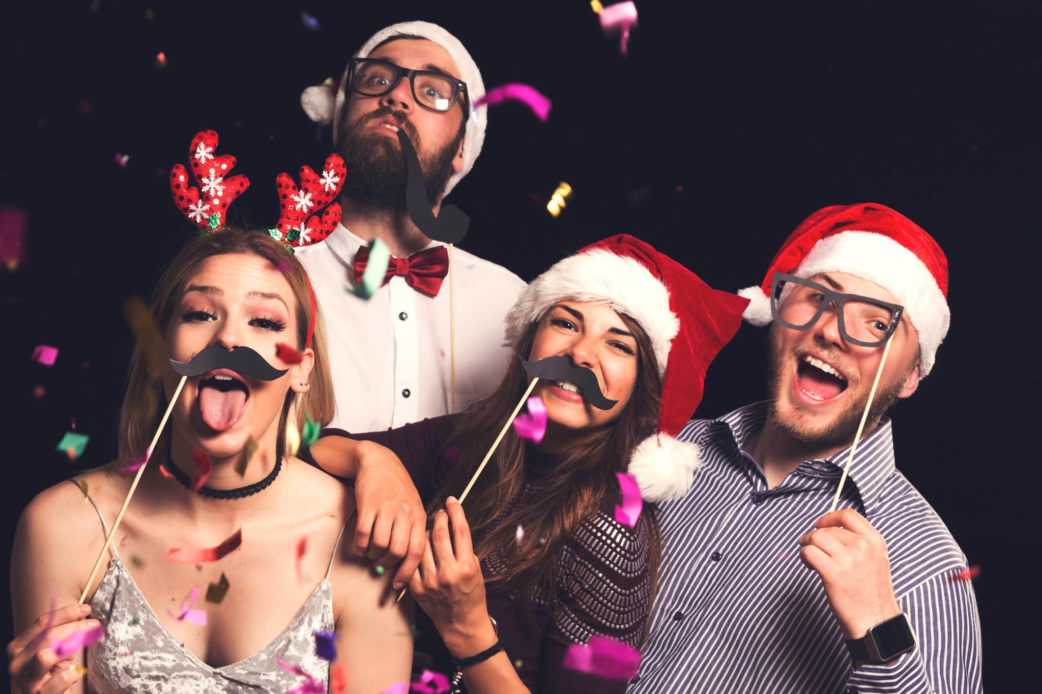 Group of friends wearing Santa hats celebrating at Christmas party