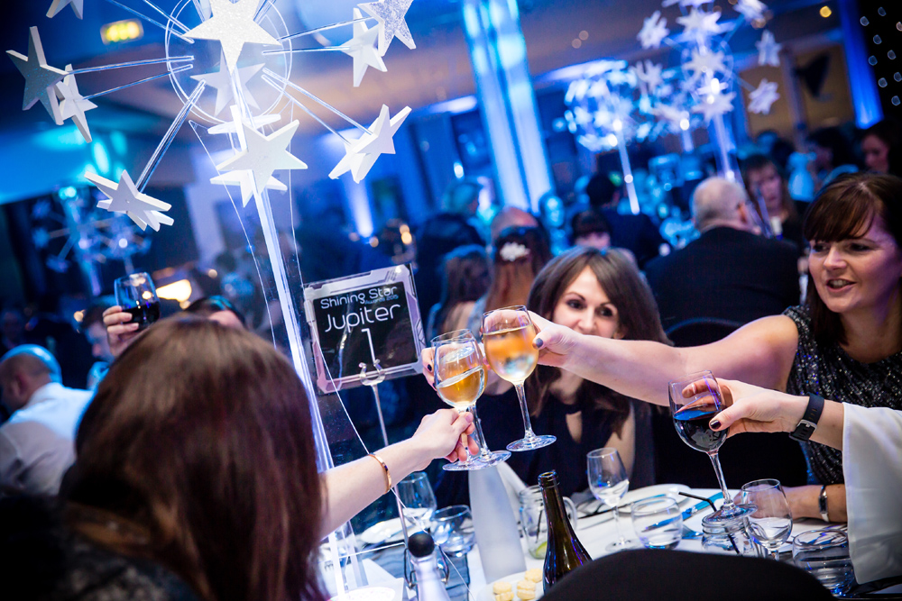 Guests raising glasses for a toast at an elegant evening event.