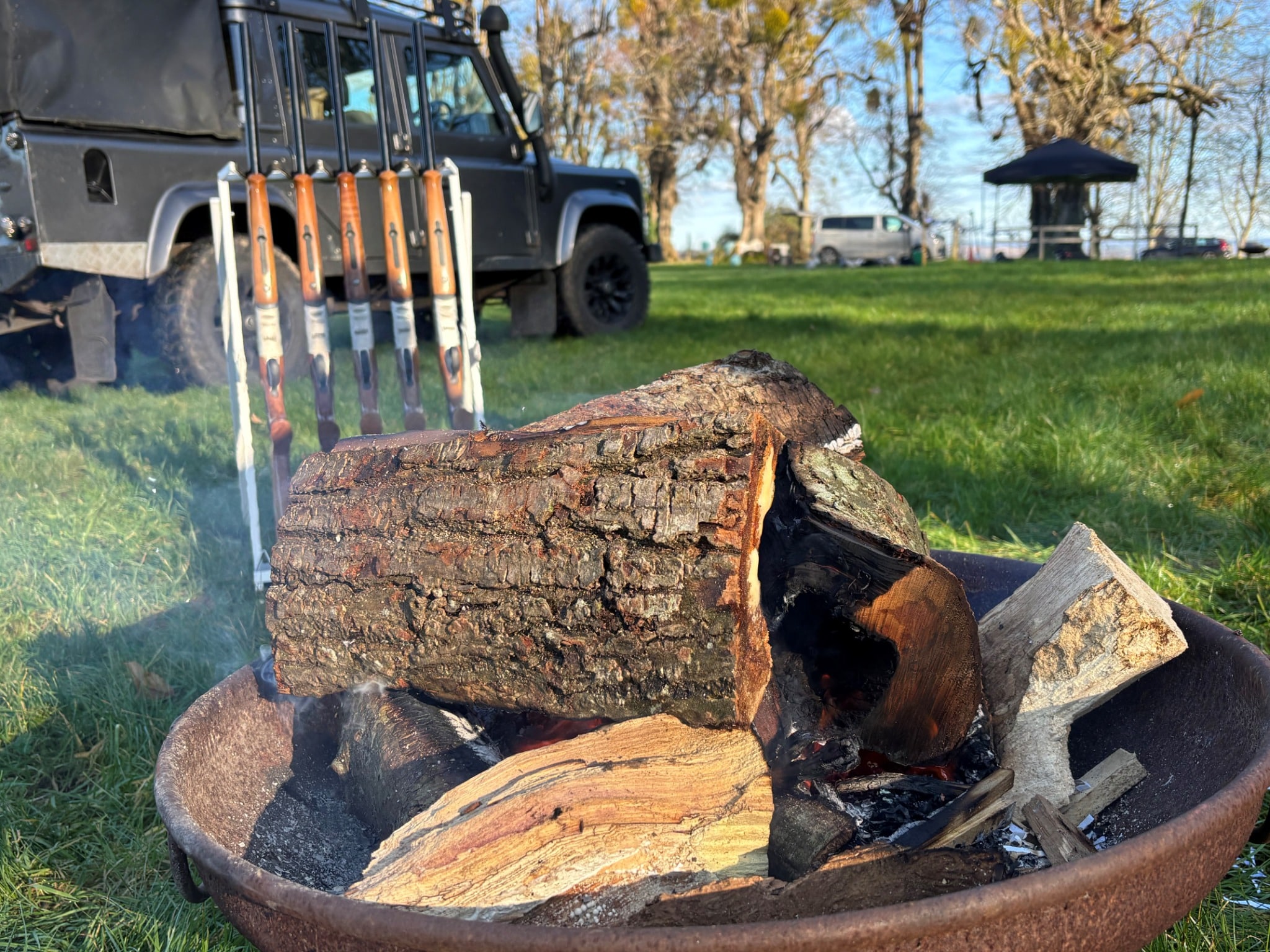 Outdoor team building activity with campfire, rifles and 4x4 vehicle in countryside setting