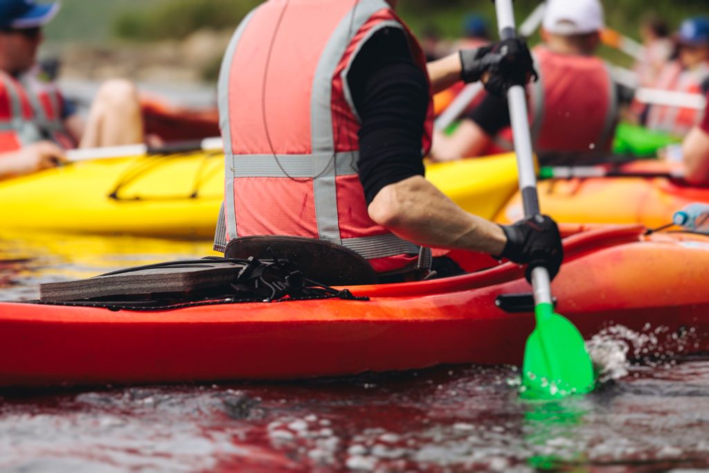 Team kayaking activity with participants paddling in colourful boats on river