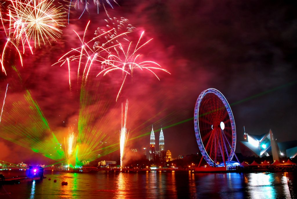 Fireworks over city skyline with ferris wheel at night