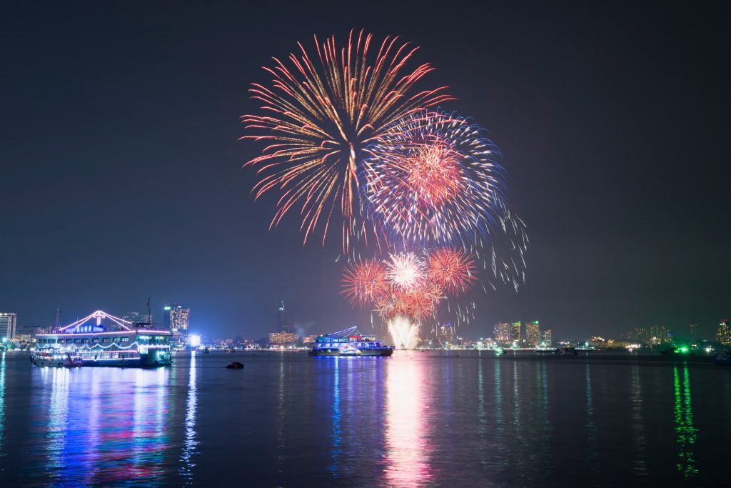 Fireworks over water with boats and city lights at night