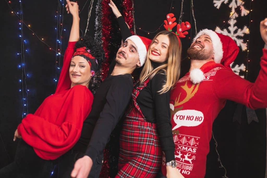 Group of colleagues celebrating at a festive Christmas party in Santa hats and seasonal outfits during a corporate event