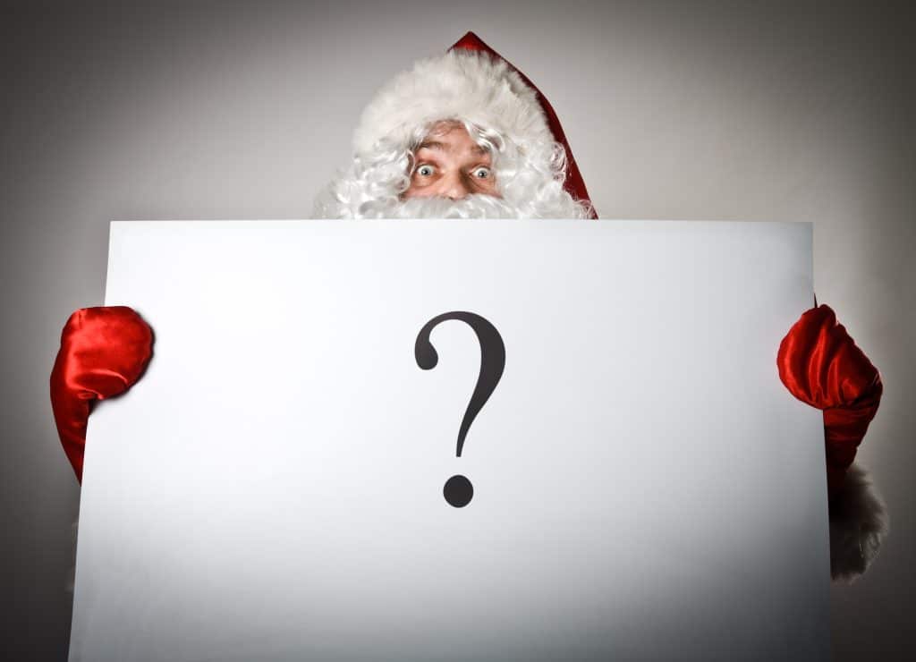 Santa Claus holding a large question mark sign for a festive Christmas quiz at a corporate event