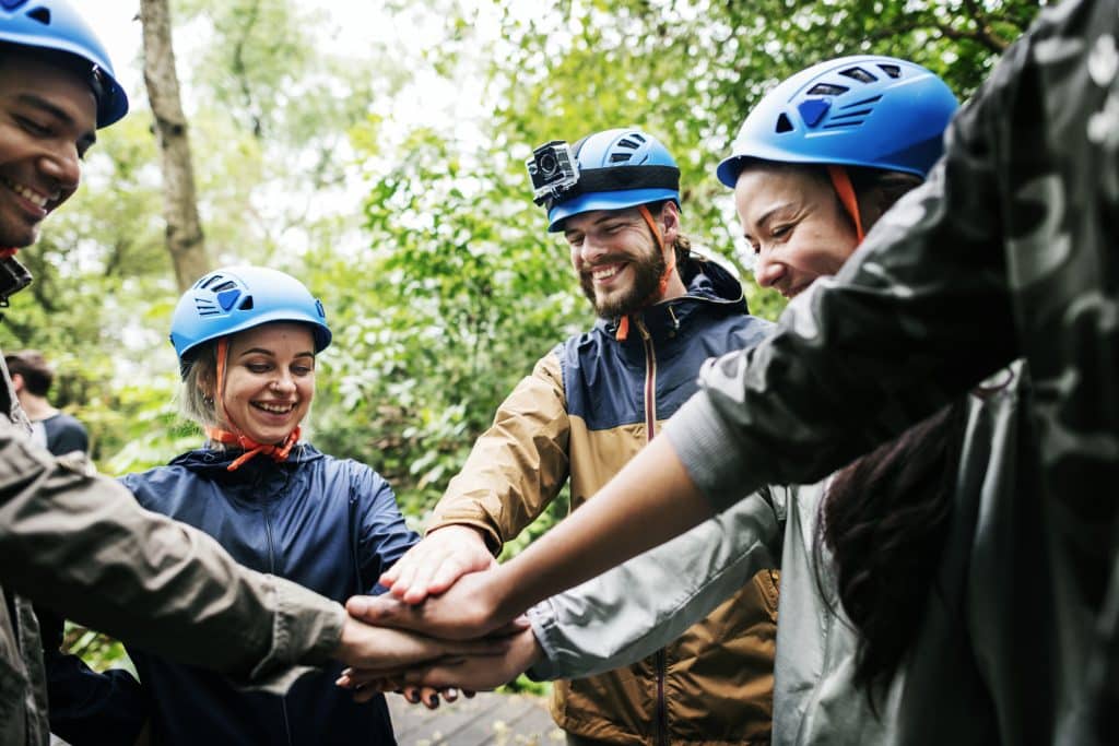 Group wearing helmets joining hands during an outdoor team building event